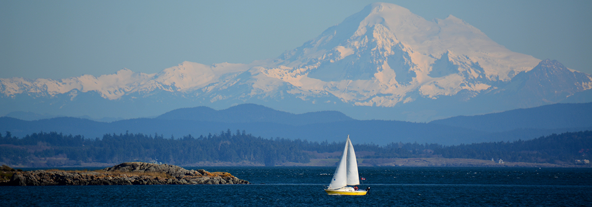 Sail boat on body of water with a mountain in the background
